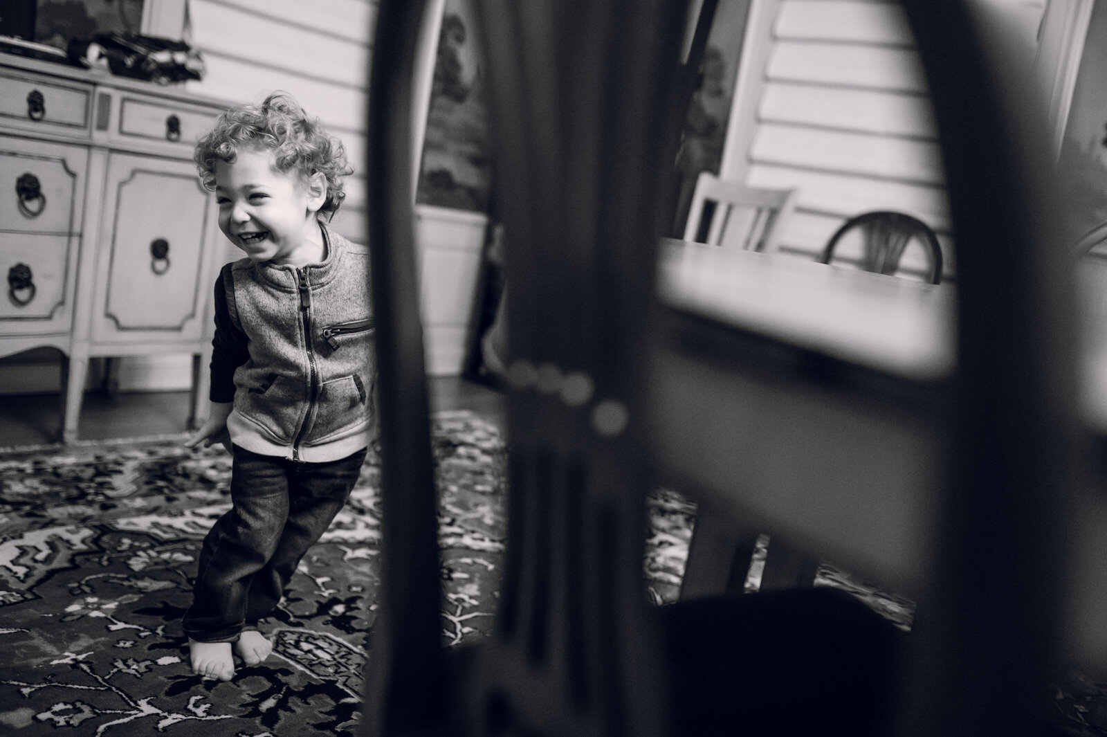 little boy laughing next to a table