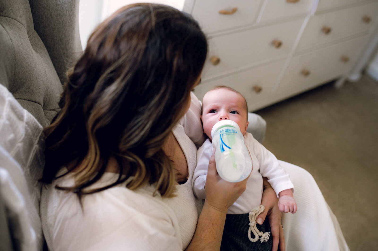 baby looking at mom while being fed a bottle